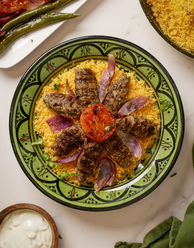 Lamm-Kebabs auf Harissa-Couscous mit gegrillten Tomaten und roten Zwiebeln
