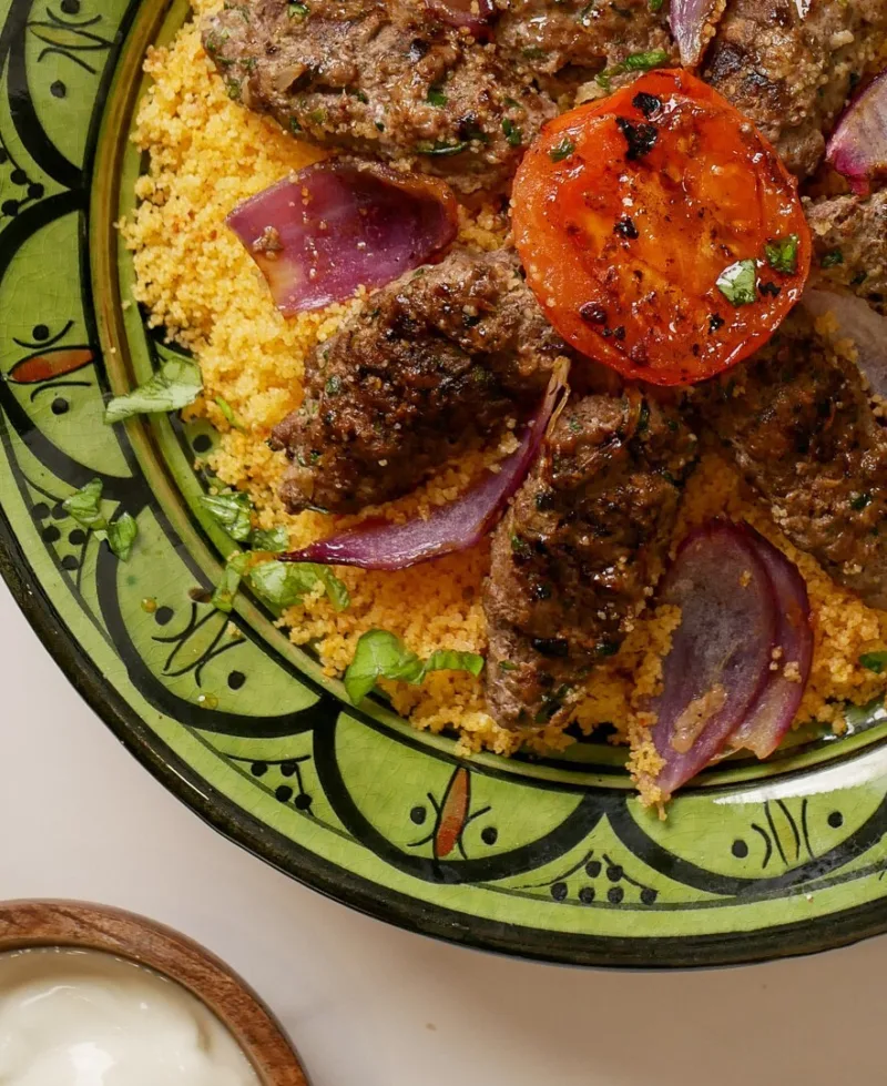 Lamm-Kebabs auf Harissa-Couscous mit gegrillten Tomaten und roten Zwiebeln